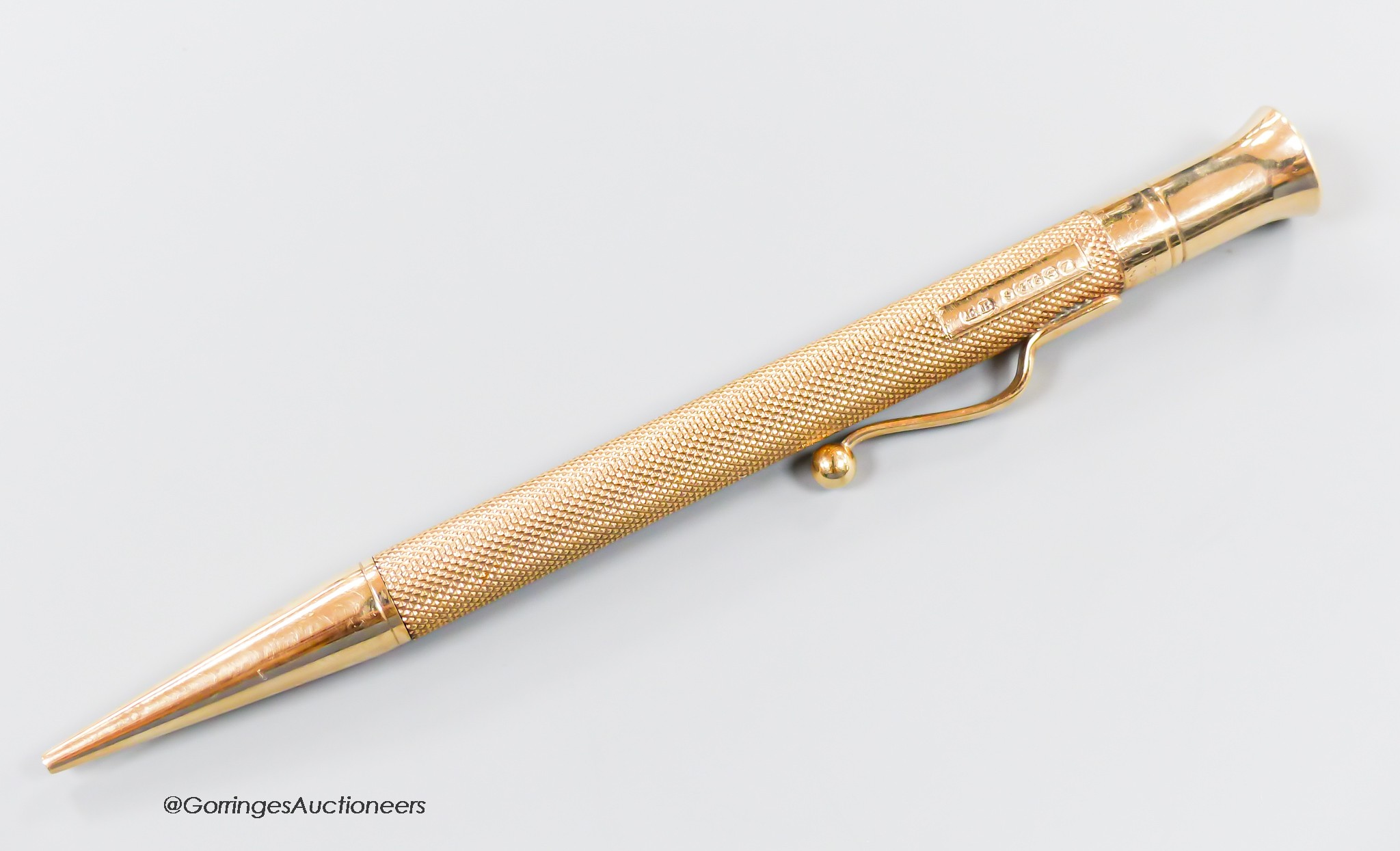 A late 1940's engine turned 9ct gold cased pencil, with engraved initials, 12.1cm.
